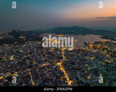 Aerial view of the illuminated cityscape of Udaipur at night, featuring ...