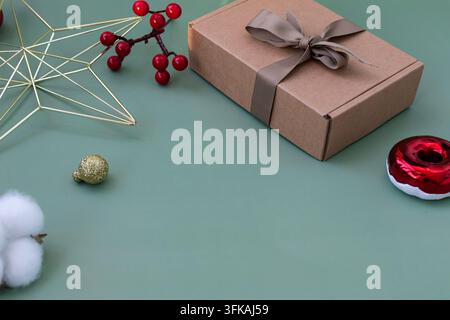 Christmas Gift Box with Ribbon and Festive Decorations on Green Background Stock Photo