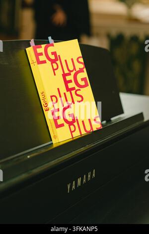 09.20.2026, Bad Hersfeld, Germany, Bright yellow songbook titled EG PLUS placed on music stand of black Yamaha piano inside church. Church music Stock Photo