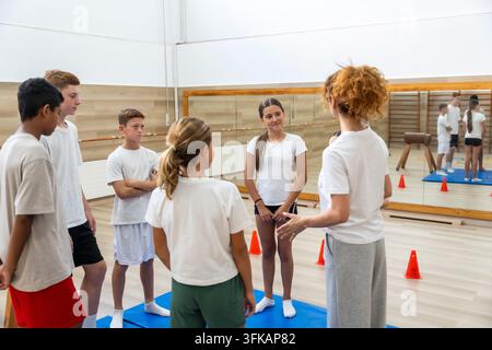 Coach instructing children during physical education class in gym Stock Photo