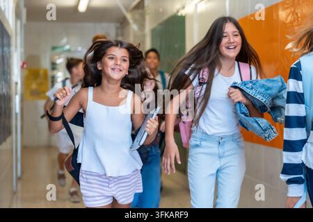 Happy school children running and laughing in corridor Stock Photo