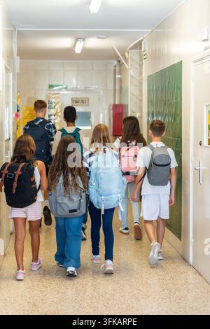 School children walking in hallway wearing backpacks Stock Photo