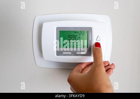hand lowering the indoor temperature in Celsius on an air conditioner thermostat, cooling, temperature control, energy saving, comfort, indoor climate Stock Photo
