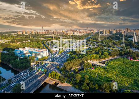 Aerial panoramic view of Beijing's urban multi-level transportation and eco-friendly livable cityscape under golden sunset glow Stock Photo