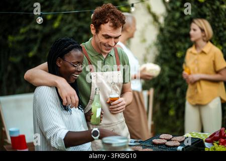 Happy diverse friends grilling burgers at backyard barbecue party Stock Photo