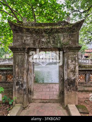 Ancient stone archway at the Temple of Emperor Le Dai Hanh in Hoa Lu Ancient Capital, Ninh Binh, Vietnam, featuring a tranquil garden pond with a foun Stock Photo