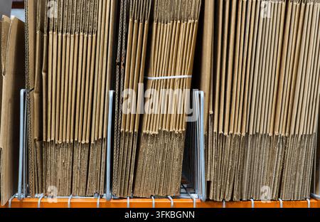 Unmade cardboard boxes of different sizes stacked on a warehouse shelf rack. Stock Photo