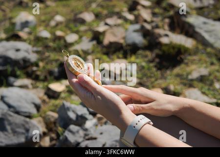 Person's hands holding an antique golden compass, pointing the needle for finding direction and showing guidance during a journey through rough natura Stock Photo