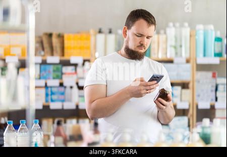 Male buyer scans code on cough syrup to check expiration date Stock Photo