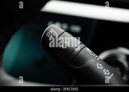 Macro photograph of a black car steering column stalk lever featuring turn signal arrows, high beam headlight switch, and SET CLR trip computer menu b Stock Photo