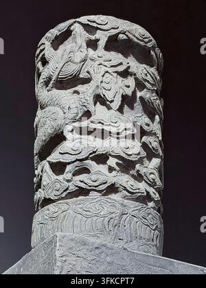 Nanjing, China - September 24, 2026: Carved stone column fragment covered in dragon and cloud relief against a black background Stock Photo