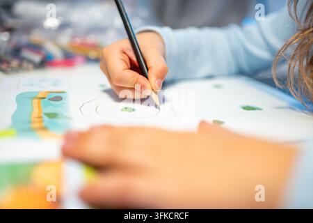 First grade student practices writing letters with pencil in workbook. Early literacy and handwriting skills develop with selective focus and shallow Stock Photo