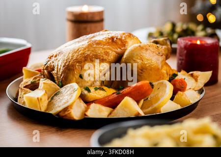 Whole roasted chicken with potatoes and vegetables on festive dinner table Stock Photo