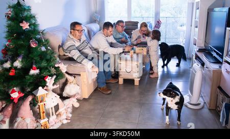Multigenerational family gathering, celebrating christmas at home, playing jenga with two dogs nearby Stock Photo