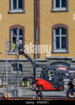 Man on a cherry picker attending to cabling with other worker on the street below in Stavanger, Norway. Stock Photo