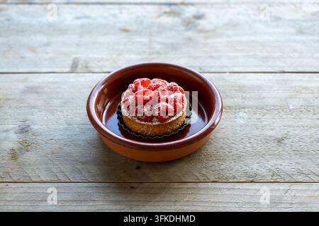 Raspberry Tart with Powdered Sugar on Rustic Table Stock Photo