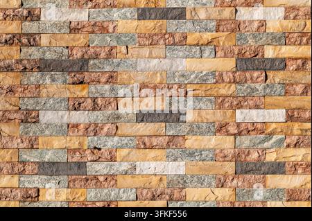Multicolored stacked stone tiles arranged in horizontal pattern on wall. Stock Photo