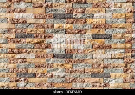 Multicolored stone brick wall arranged in horizontal course pattern. Stock Photo