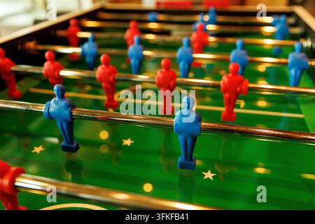 A close-up shot of a table football game showing red and blue plastic figure players aligned on metal rods. Stock Photo