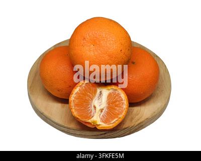 Fresh mandarin oranges stacked on a round wooden plate with a half-peeled orange in front, isolated on a white background Stock Photo