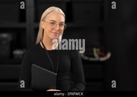 Professional female IT consultant with tablet in a dark studio, ready for tech and cybersecurity topics Stock Photo