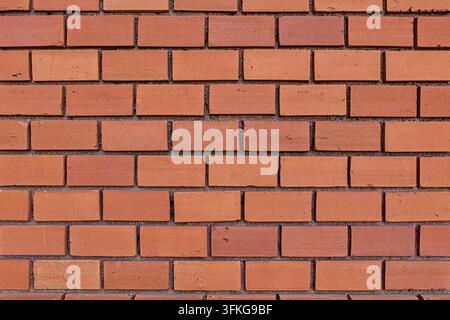 Texture and pattern of a bright brick wall, classic brick masonry in warm orange-brown shades, building material. Stock Photo