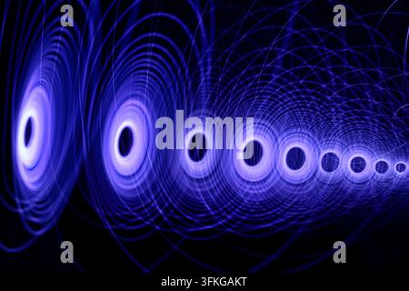 Abstract light effect with swirling blue light circles and spirals on a dark background, modern digital graphics and energy. Stock Photo