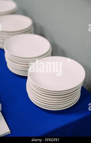 Stacks of white ceramic plates on a blue tablecloth Stock Photo