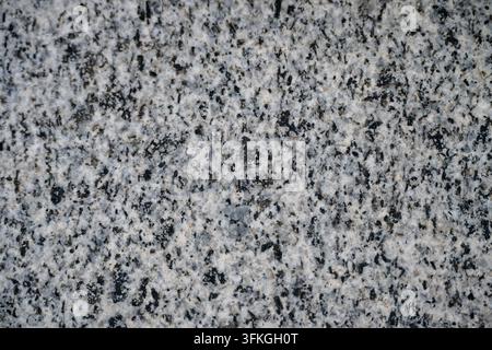 A full-frame macro view displaying the textured surface of polished gray granite, characterized by dense, speckled patterns of white, gray, and black Stock Photo