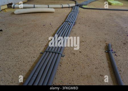 Electrical conduits and cable protection pipes arranged on concrete floor during building installation work in Germany, showing organized electrical i Stock Photo
