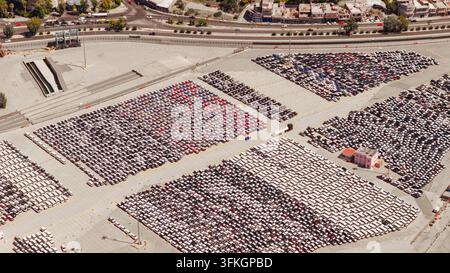 Large outdoor car storage at Piraeus port showing rows of new vehicles ready for export; aerial view highlighting scale of automotive logistics and in Stock Photo
