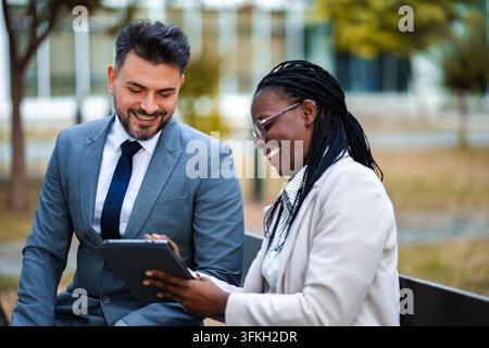 Diverse business colleagues working together outdoors using tablet Stock Photo