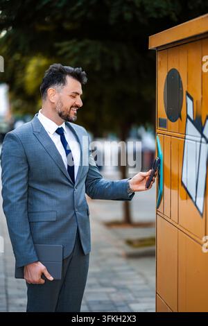 Businessman using smartphone for parcel locker delivery Stock Photo