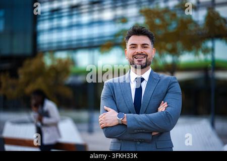Confident businessman standing with arms crossed in urban setting Stock Photo