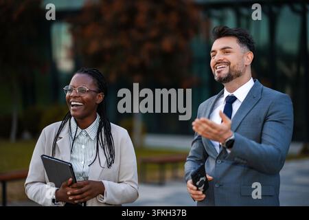 Diverse business professionals laughing outdoors discussing business Stock Photo