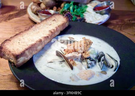 Halifax Nova Scotia Canada,Argyle Street,seafood chowder,creamy soup,mussels,salmon,fish,toast,grilled bread,dill,celery,black bowl,wooden table,resta Stock Photo