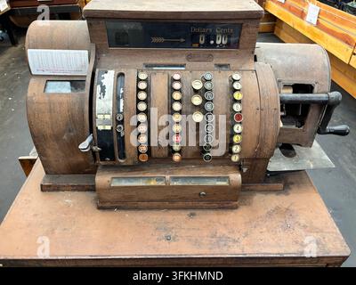 A heavily rusted vintage mechanical adding machine featuring rows of numbered keys and a hand crank, preserving early office history Stock Photo