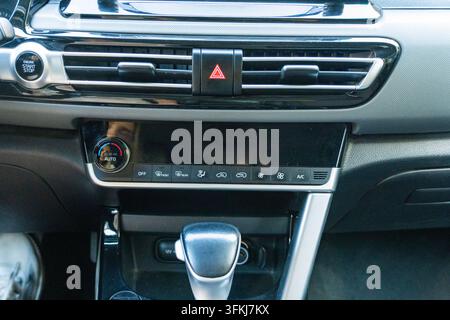 Close-up of a modern car interior showing dashboard center console, air conditioning control buttons, engine start stop button, and gear shift. Concep Stock Photo