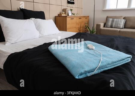 Blue electric heating pad on bed in room Stock Photo
