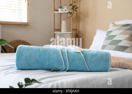 Folded electric heating pad on bed in room Stock Photo