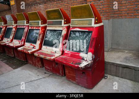 Perspective view of rows of red arcade machines along a street wall Stock Photo