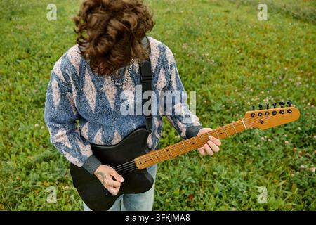 Man Playing Electric Guitar Outdoors in Meadow for Indie Music Concept Stock Photo