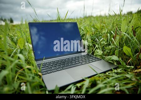 Modern Laptop with Blank Screen Placed on Green Grass Outdoors Stock Photo