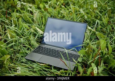 Laptop with Blank Screen Placed on Green Grass Outdoors Stock Photo