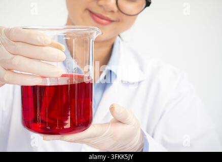 Close up of young female scientist with flask making test or research in clinical laboratory. Science, chemistry, biology, medicine and people concept Stock Photo