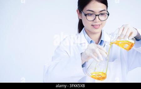 Life scientists researching in laboratory. Focused female life science professional pipetting solution into the glass cuvette. Lens focus on researche Stock Photo