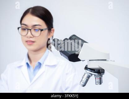 Selective focus of microscope with young Asian woman working in lab blur behide. Scientist doctor making medical research. Laboratory tools: microscop Stock Photo
