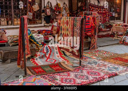 A vibrant display of traditional Caucasian carpets and rugs with geometric patterns, hanging and laid out at an outdoor market. The colorful textiles Stock Photo