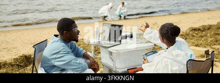 Header of Black Ecologists Analyzing Water Samples with Laptop Outdoors Stock Photo