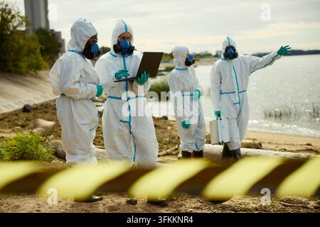 Ecologists in Hazmat Suits Analyzing Water Pollution Data Stock Photo